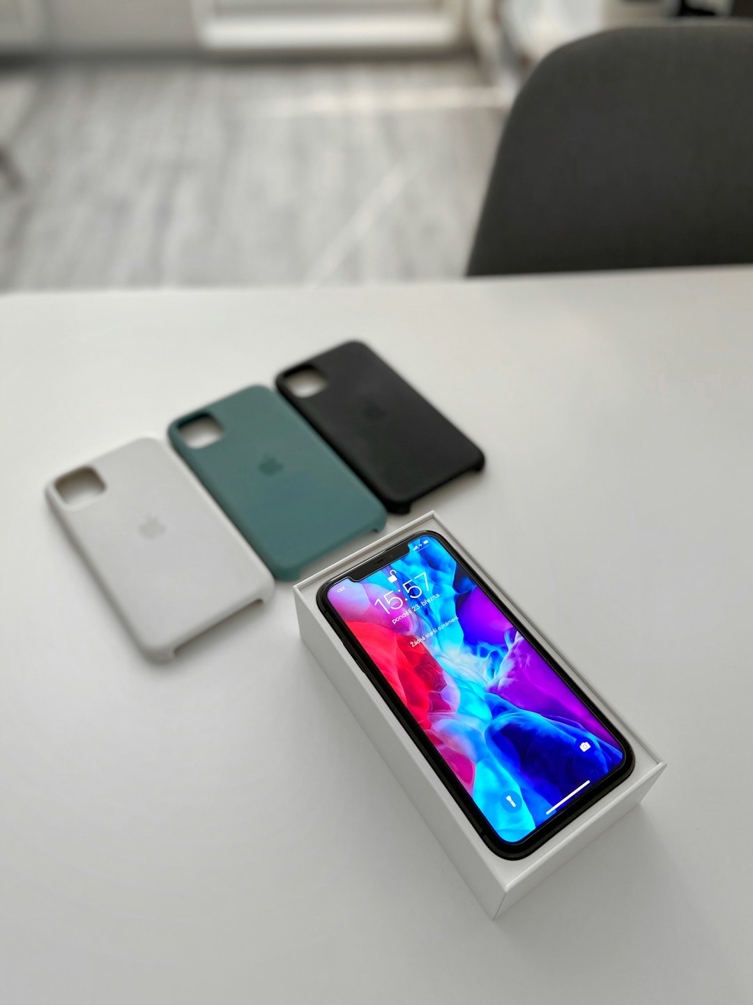 Nowoczesny smartfon w pudełku z trzema silikonowymi etui na stole.