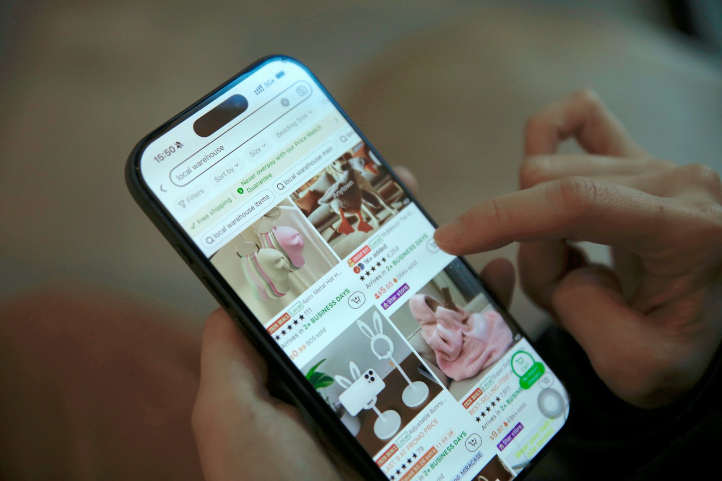 Dłonie stukające w aplikację zakupów online na smartfonie.